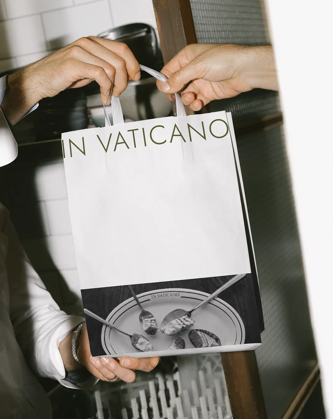 Фирменный бумажный пакет in Vaticano в руках гостей