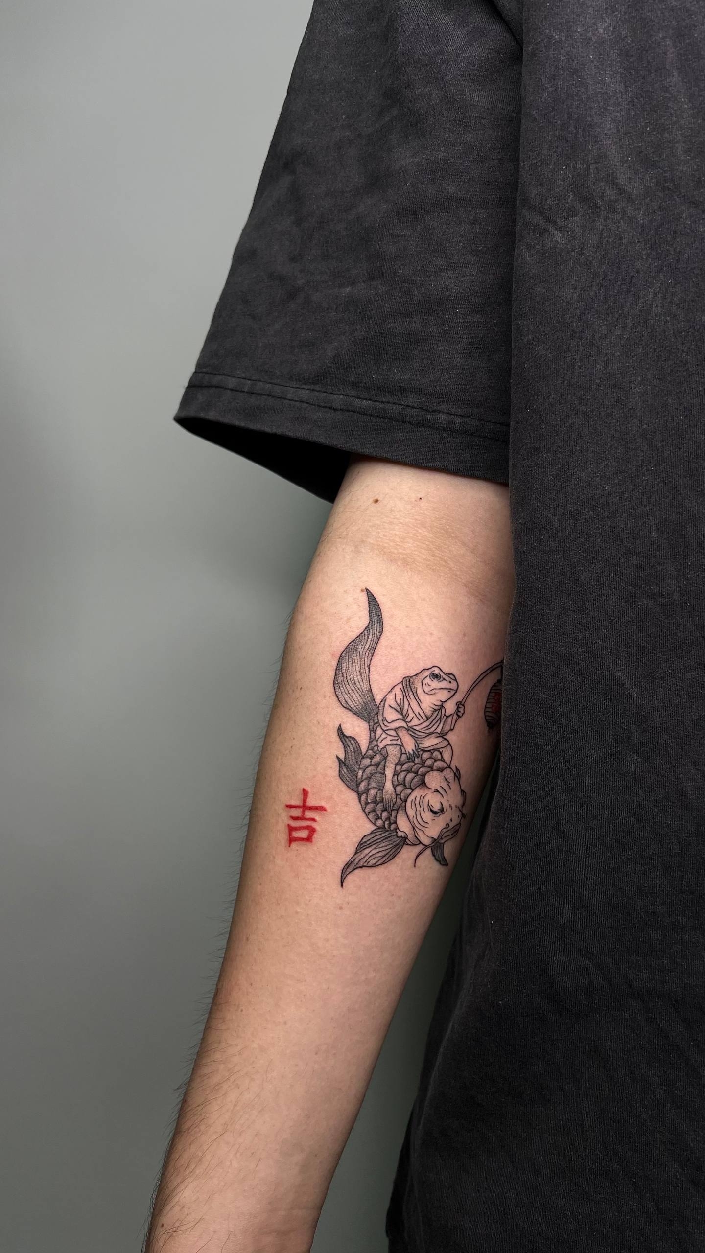 Koi fish with red character tattoo on forearm