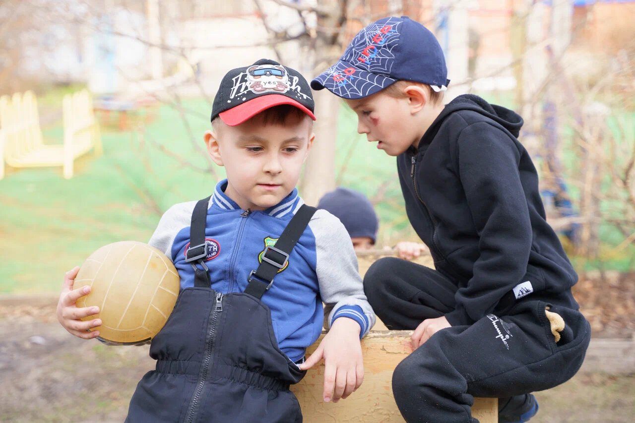 Мальчики играют с мячом на площадке детского сада