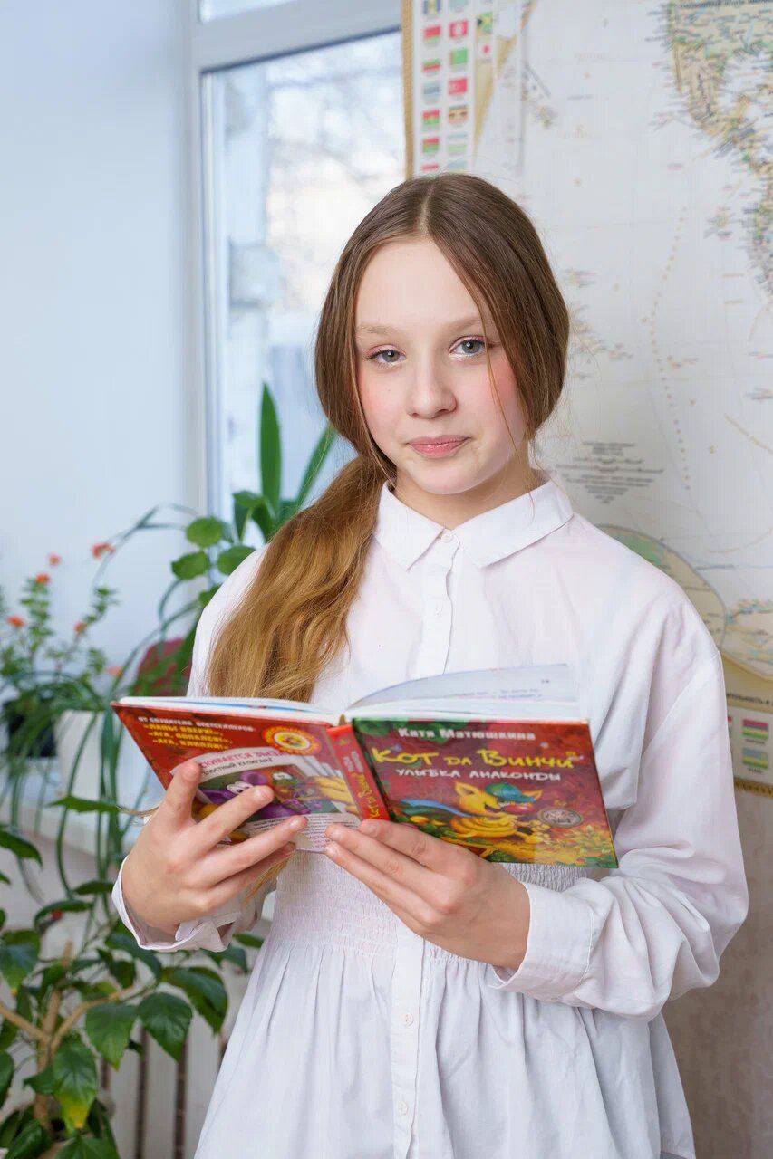 Ученица 4 класса читает книгу у окна класса