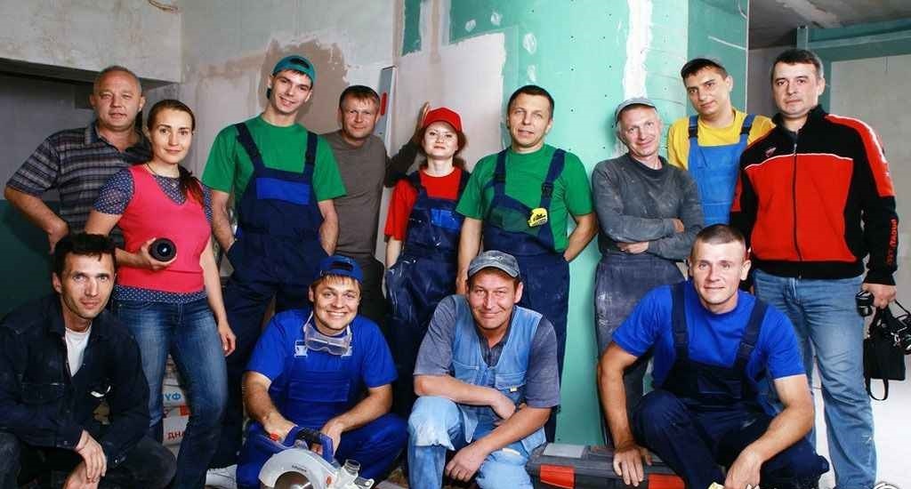 Большая бригада строителей из 12 человек в спецодежде на объекте